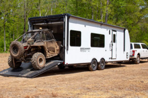 An ATC Toy Hauler loads a jeep into its cargo space.